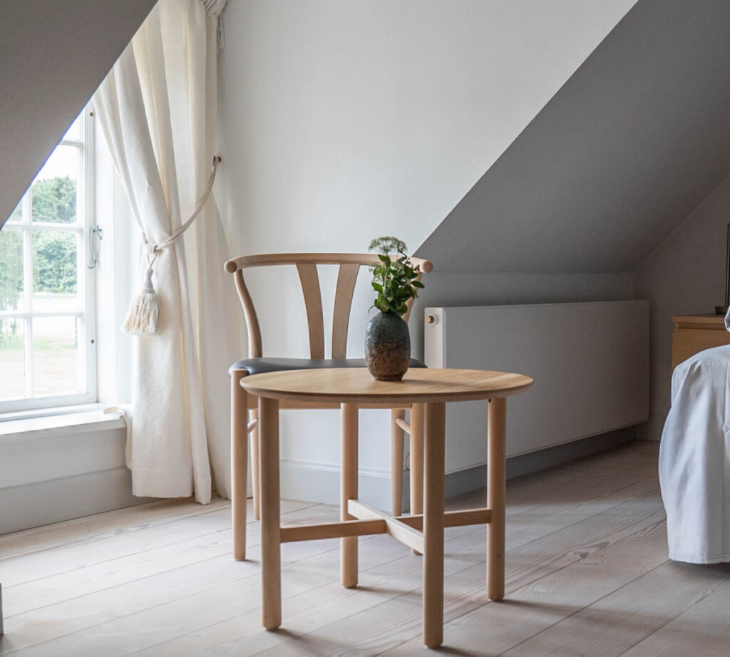 Lille bord og stol ved vindue med skråvæg og naturligt lys